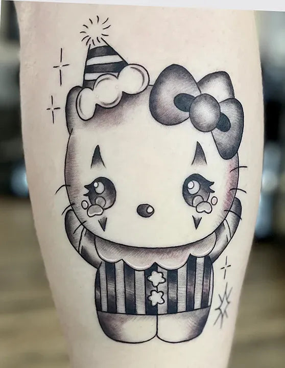 Black-and-grey tattoo of Hello Kitty dressed as a crying clown in a party hat and ruff collar.