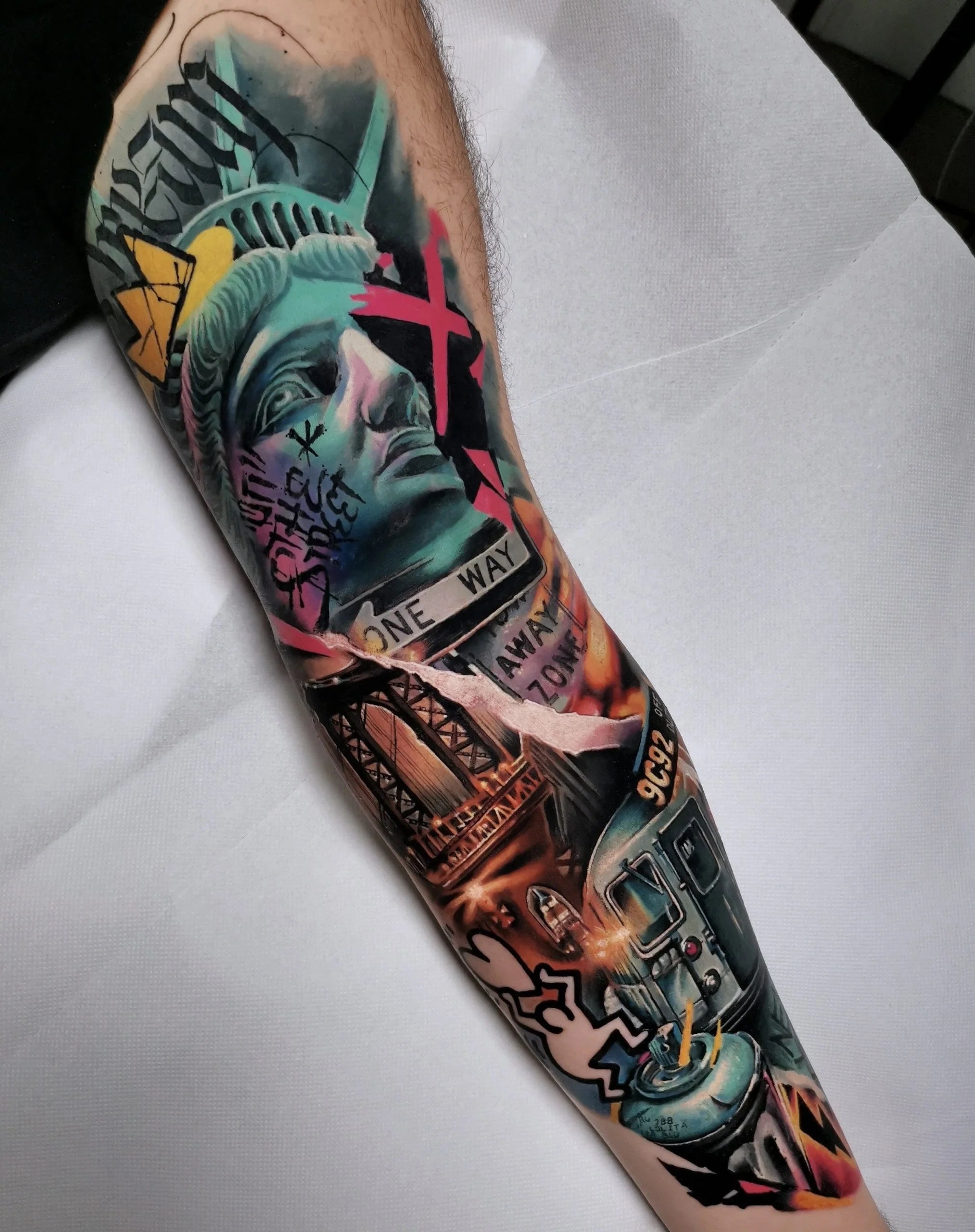 A colorful, graffiti-inspired New York City themed tattoo sleeve featuring the Statue of Liberty with vibrant neon blue and pink highlights, the Brooklyn Bridge, a subway car, and street art elements.