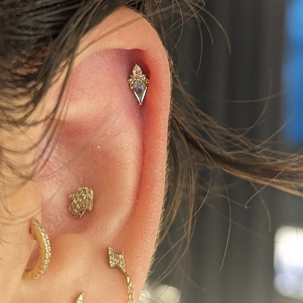 Curated ear set featuring a kite-cut light blue sapphire with diamond accents, paired with a detailed gold Hamsa hand stud.